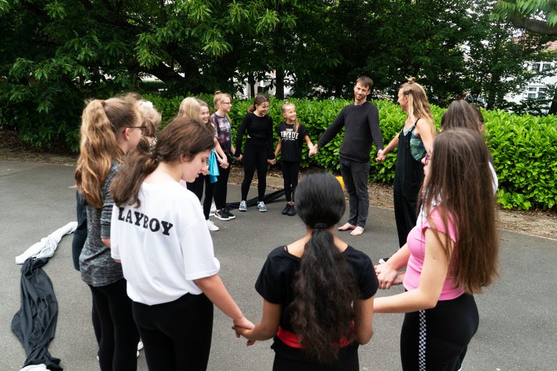 Artist duo Webb-Ellis stand hand-in-hand in a circle with a group of 15 teenagers as part of a workshop.